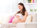 Pregnant smiling woman sitting on a sofa Royalty Free Stock Photo