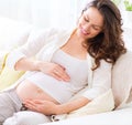 Pregnant smiling woman sitting on a sofa Royalty Free Stock Photo