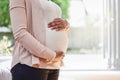 Pregnant, stomach and woman frame her belly or ready for motherhood or hands on tummy in the living room at home