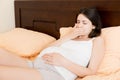 Pregnant suffering with nausea. Pregnancy symptoms, expectation toxicosis. Young vomiting woman sitting on bed. parenthood concept Royalty Free Stock Photo