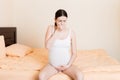 Pregnant suffering with nausea. Pregnancy symptoms, expectation toxicosis. Young vomiting woman sitting on bed. parenthood concept Royalty Free Stock Photo