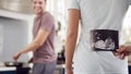 Pregnant Transgender Couple At Home In Kitchen With Woman Surprising Man With Ultrasound Scan Of Baby Royalty Free Stock Photo