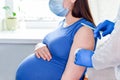 Pregnant Vaccination. Pregnant Woman In Face Mask Getting Vaccinated in Hospital. Doctor Giving Corona Virus Vaccine Injection Royalty Free Stock Photo