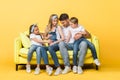 Pregnant wife, husband and children sitting on sofa on yellow Royalty Free Stock Photo