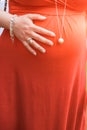 Pregnant woma with red clothes and a bell