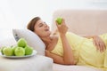 Pregnant woman, apple and smile on sofa for health, nutrition and wellness in living room of apartment. Person, fruit Royalty Free Stock Photo