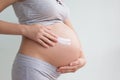 A pregnant woman applies stretch marks cream to her stomach. Stretch marks. Striae. Moisturize the skin during pregnancy. Body Royalty Free Stock Photo