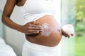 Pregnant woman applying cream on her belly Royalty Free Stock Photo