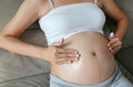 Pregnant woman applying cream on her belly skin. Moisturize dry skin during pregnancy Royalty Free Stock Photo