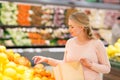 Pregnant woman with bag buying oranges at grocery Royalty Free Stock Photo