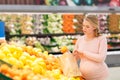 Pregnant woman with bag buying oranges at grocery Royalty Free Stock Photo