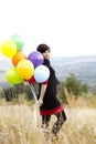 Pregnant woman with balloons in grass Royalty Free Stock Photo