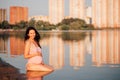 a pregnant woman on the beach, A beautiful, smiling pregnant woman in a pink swimsuit is sitting on her knees in the Royalty Free Stock Photo