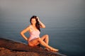 pregnant woman on the beach, charming, smiling pregnant woman in a pink swimsuit posing and playing with dark hair Royalty Free Stock Photo