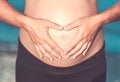 Pregnant woman beach - hands in heart shape on belly Royalty Free Stock Photo