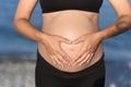 Pregnant woman beach - hands in heart shape on belly Royalty Free Stock Photo