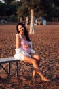 a pregnant woman on the beach, a happy, beautiful pregnant woman in a pink swimsuit and a white shirt sitting on a bench Royalty Free Stock Photo