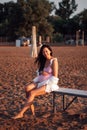 a pregnant woman on the beach, Smiling, attractive, leggy pregnant woman in a pink swimsuit and a white shirt sitting on Royalty Free Stock Photo