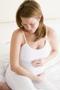 Pregnant woman on bed holding stomach in pain Royalty Free Stock Photo