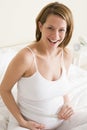 Pregnant woman in bedroom measuring belly Royalty Free Stock Photo