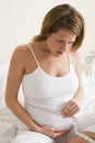 Pregnant woman in bedroom measuring belly Royalty Free Stock Photo