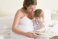 Pregnant woman in bedroom reading book with daught Royalty Free Stock Photo