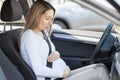 Pregnant woman behind the steering wheel having contractions