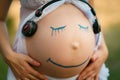 Pregnant woman belly closeup with smiling funny face drawing on