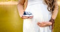 Pregnant woman belly holding baby booties. Healthy pregnancy.