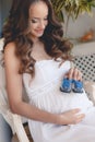 Pregnant woman belly holding baby booties. Royalty Free Stock Photo