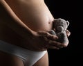 Pregnant woman belly, holding in his hand little teddy bea