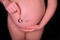 A pregnant woman on a black background with a Muslim religious symbol in her hand. The concept of choosing the religion of the