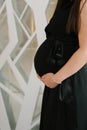 A pregnant woman in a black dress holds her hands on her stomach. Happy pregnancy Royalty Free Stock Photo