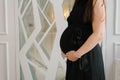 A pregnant woman in a black dress holds her hands on her stomach Royalty Free Stock Photo