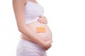 Pregnant woman with blank stick notepad on her belly, anonymous