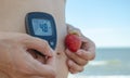 Pregnant woman with blood control meter and strawberry taking control of gestational diabetes close up