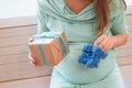 Pregnant woman in blue dress is holding gift box and blue knitted bootee. Pregnant lifestyle Royalty Free Stock Photo