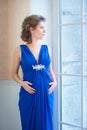 Pregnant woman in blue dress near window. Prifile Royalty Free Stock Photo