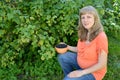 The pregnant woman with a bowl of berries of blackcurrant in a garden