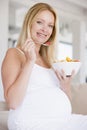 Pregnant woman with bowl of fruit salad smiling Royalty Free Stock Photo