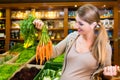 Pregnant woman buying healthy vegetables in grocer store