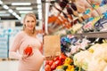 Pregnant woman buying vegetables at grocery store Royalty Free Stock Photo