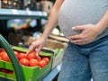 Pregnant woman buys tomatoes in the store. Royalty Free Stock Photo