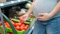 Pregnant woman buys tomatoes in the store. Royalty Free Stock Photo