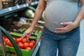 Pregnant woman buys tomatoes in the store. Royalty Free Stock Photo