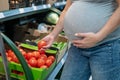 Pregnant woman buys tomatoes in the store. Royalty Free Stock Photo