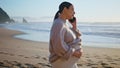 Pregnant woman calling cellphone at beach caressing big belly. Girl talking Royalty Free Stock Photo