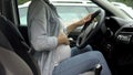 Pregnant woman in car, holding hand on belly, active baby during third trimester