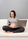 Pregnant woman with cellphone and laptop Royalty Free Stock Photo