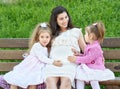 Pregnant woman and children in summer city park outdoor, happy family, bright sunny day and green grass, beautiful people portrait Royalty Free Stock Photo